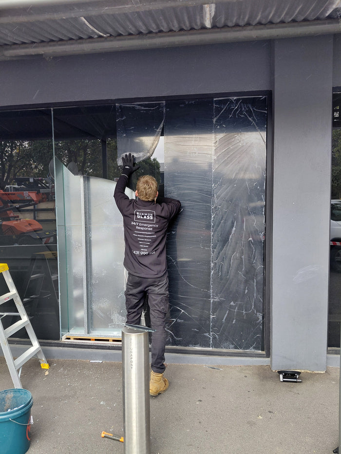 Peeling back the dark tint film that was holding a cracked float glass shopfront together at NAB Geelong West