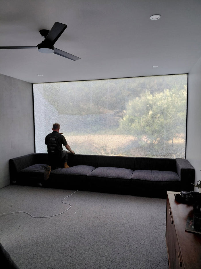 Barwon Glass glazier applying safety film across a shattered 4.5 metre double glazed panel at a Connewarre home