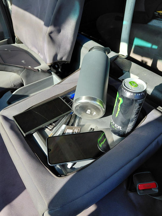 Loose phone, drink bottle, energy drink can and pens sitting in the ISUZU centre console storage pocket before fitting the organizer