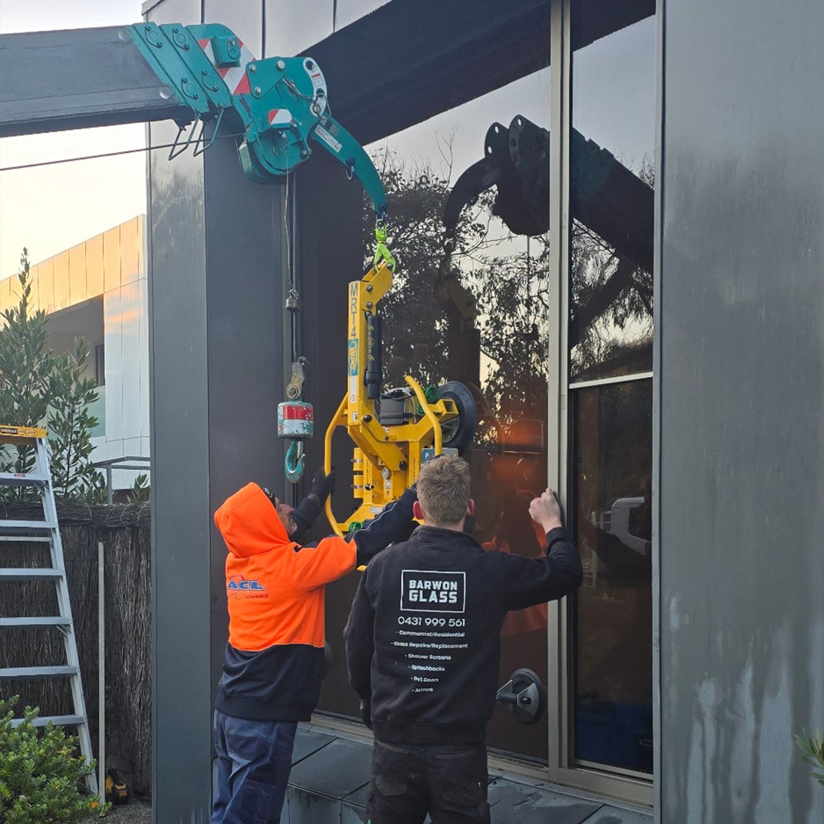 Barwon Glass technicians using a vacuum lifter to install a glass panel on a commercial job